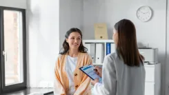 Doctor is holding a clipboard with a checklist and speaking to her patient.
