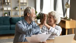 Man is holding 3 papers and high-fiving a woman